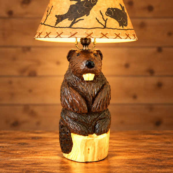 Three-quarter view of a handcrafted wooden beaver table lamp with carved fur, front teeth and a wildlife shade