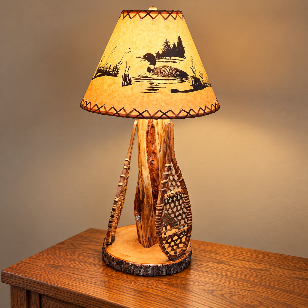 Custom Diamond Willow table lamp featuring two handcrafted snowshoes, a bark-edge wood base, and an illuminated loon shade.