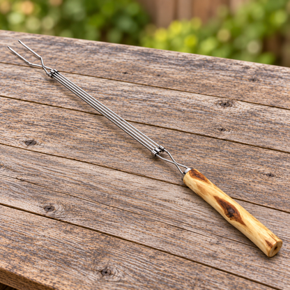 Extendable chrome-plated roasting fork with a handcrafted Diamond Willow handle on a rustic outdoor wood table.