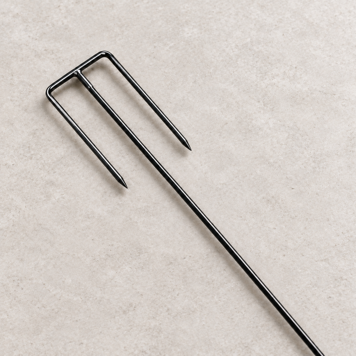 Close-up of moderately pointed inward-facing safety fork tines with a straight black metal shaft.