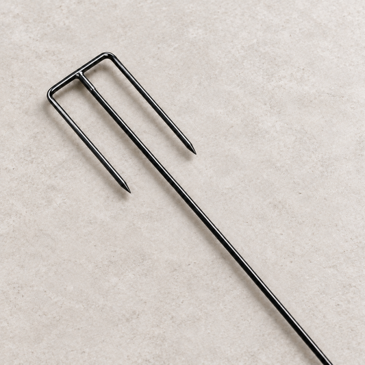 Close-up of moderately pointed inward-facing safety fork tines with a straight black metal shaft.